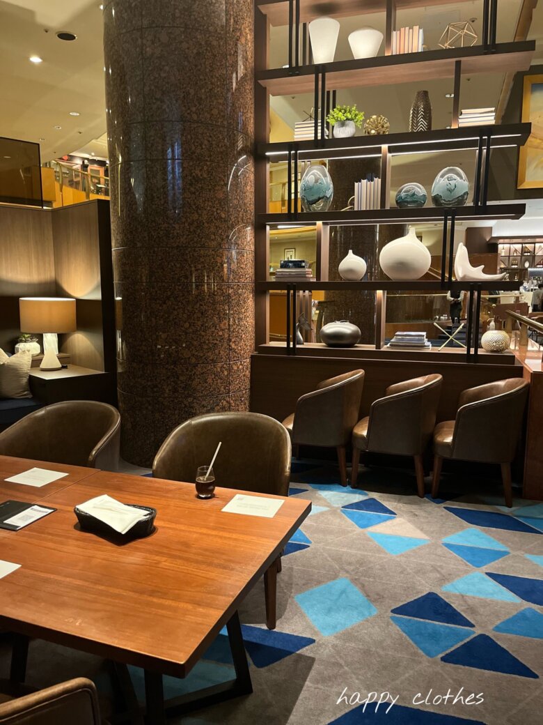 ホテルのラウンジとテーブルと青いじゅうたんと飾り棚